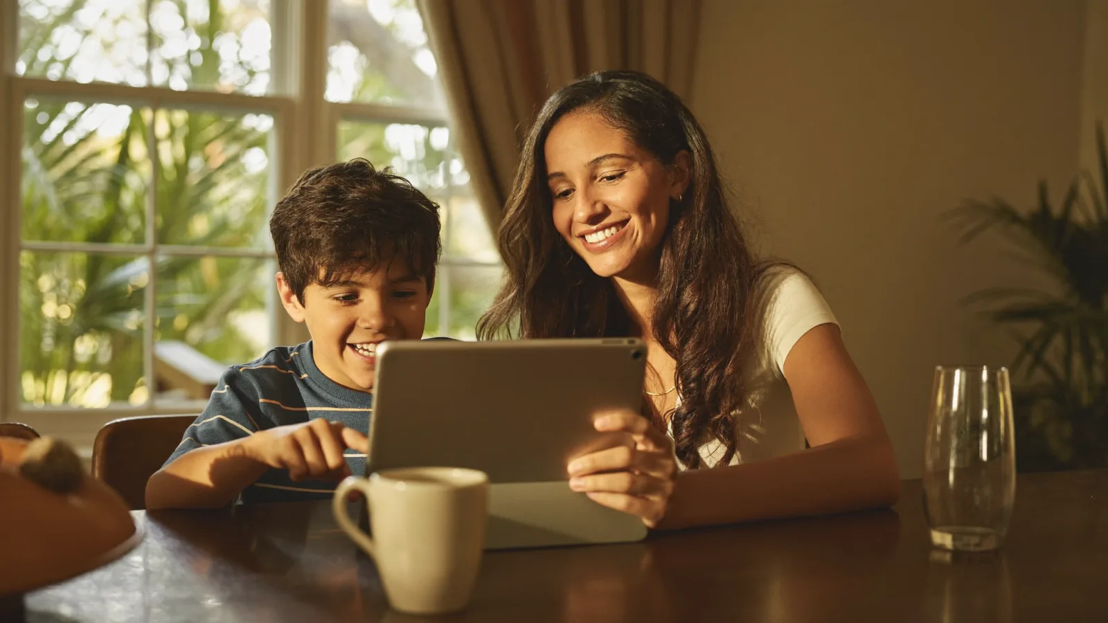 A young child and their parent sharing a tablet at home